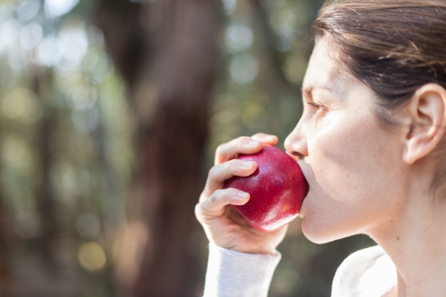 close up of woman biting an apple in the park 23 2147562315